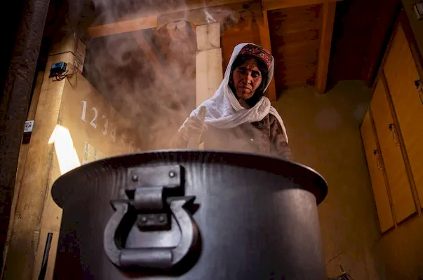A Pakistani woman stirs a pot of fermented wheat for the spring festival, highlighting the country's warm hospitality and rich culinary traditions